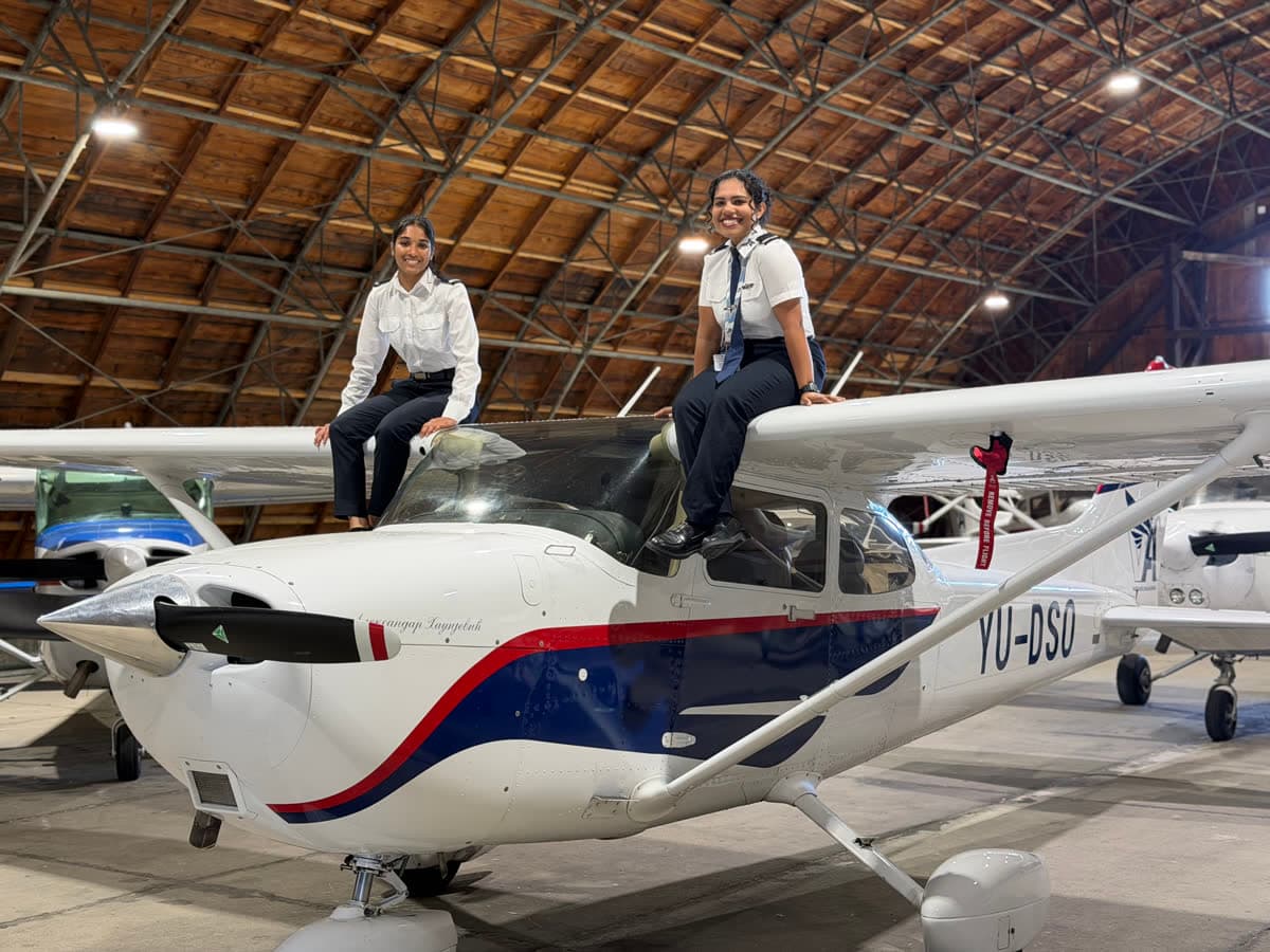 Two TATS cadets sitting on a Cessna wing