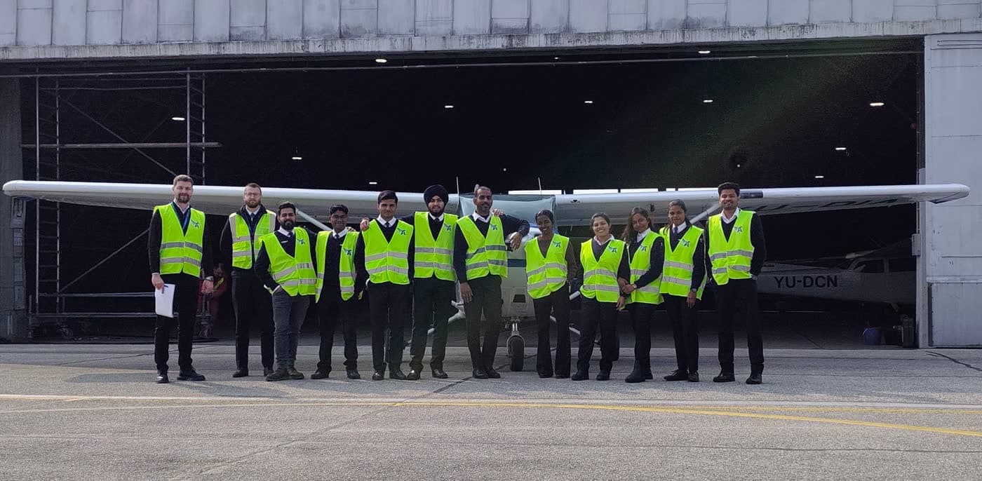 TATS cadets in high-visibility vests in front of an aircraft hangar